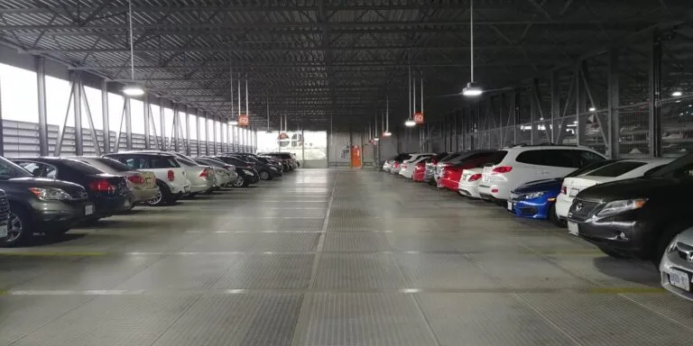Parked cars beneath a high exposed metal truss roof in a covered garage