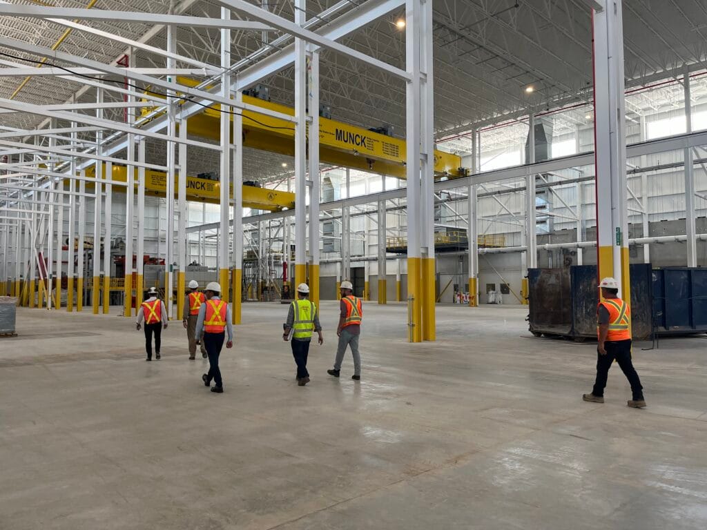 Broad interior view of a large high-bay industrial facility with roof steel